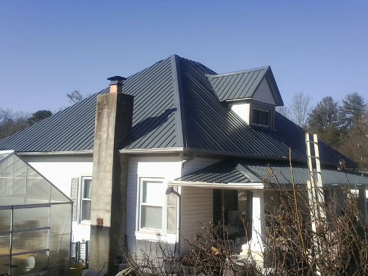 Dark blue standing seam metal roof on a white farmhouse with dormer — Slate & Tile Roof Repair by Roofing Brothers in Dennis