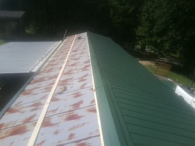 Old rusted panels beside newly installed green metal roofing — Wind Damage Roof Repair by Roofing Brothers in Dennis