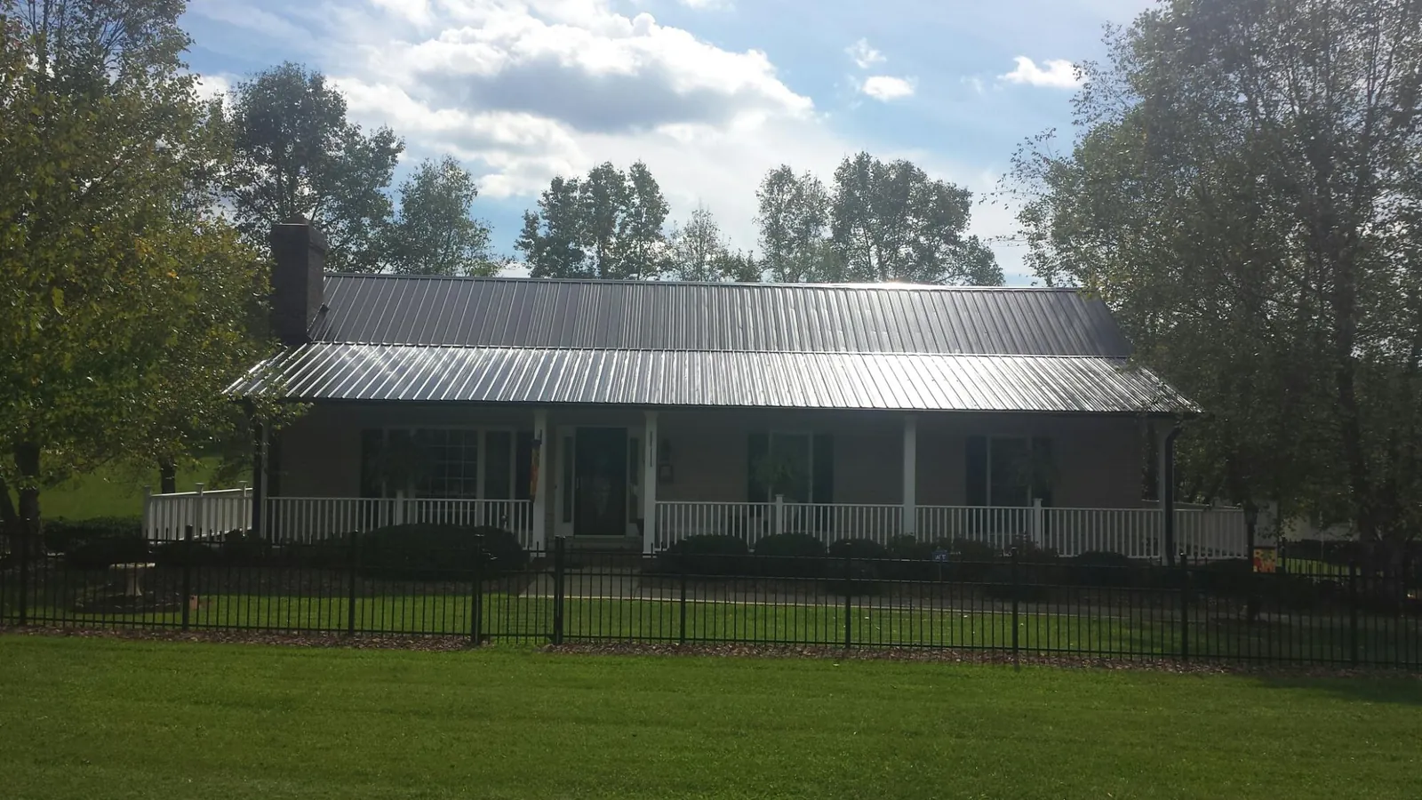 Gray metal roof on a brick ranch with a full width front porch — Gutter Guard Installation work by our crew in Dennis