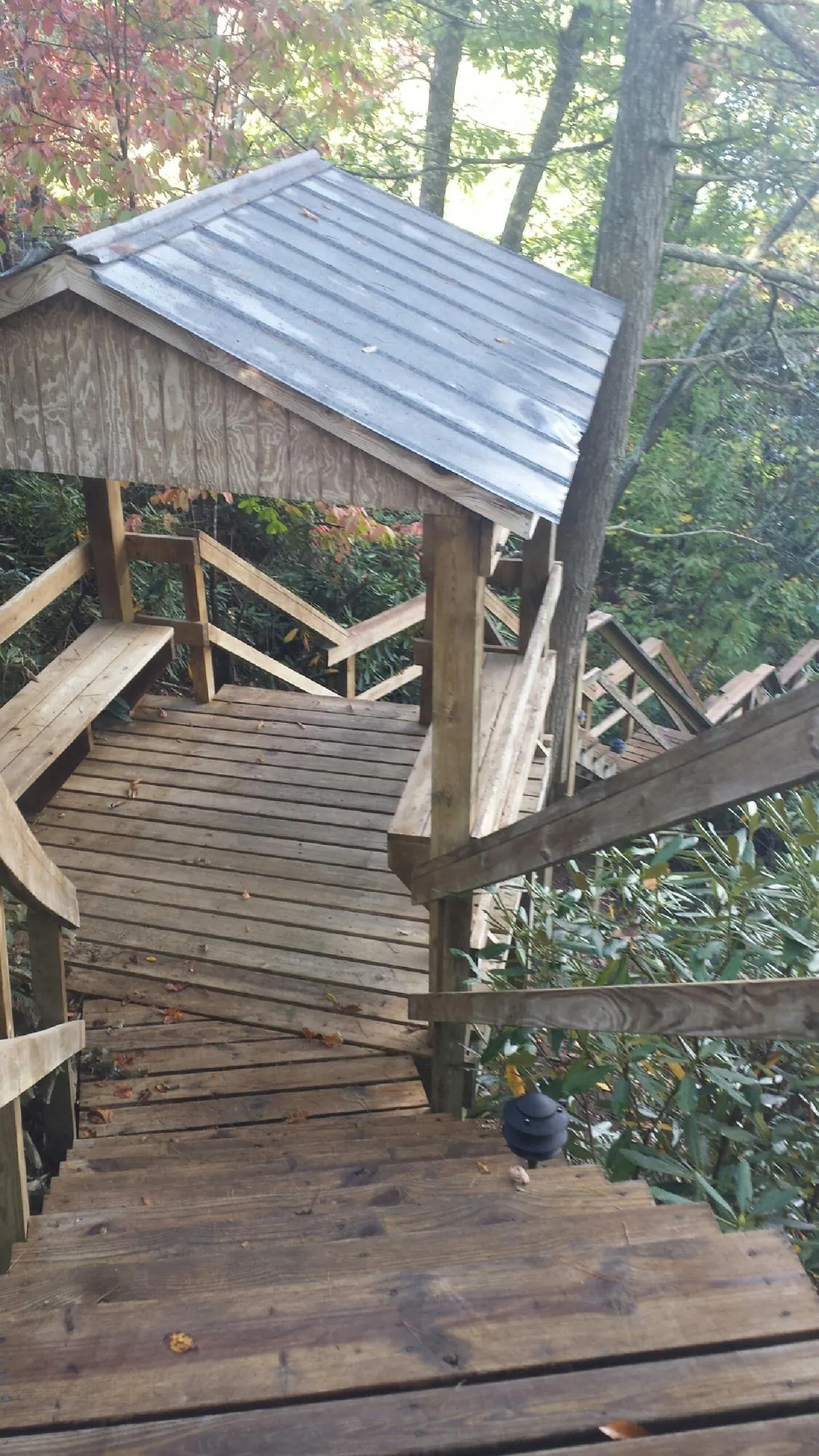 Metal roofed shelter over wooden steps on a wooded walkway — Skylight Repair & Installation work by our crew in Dennis